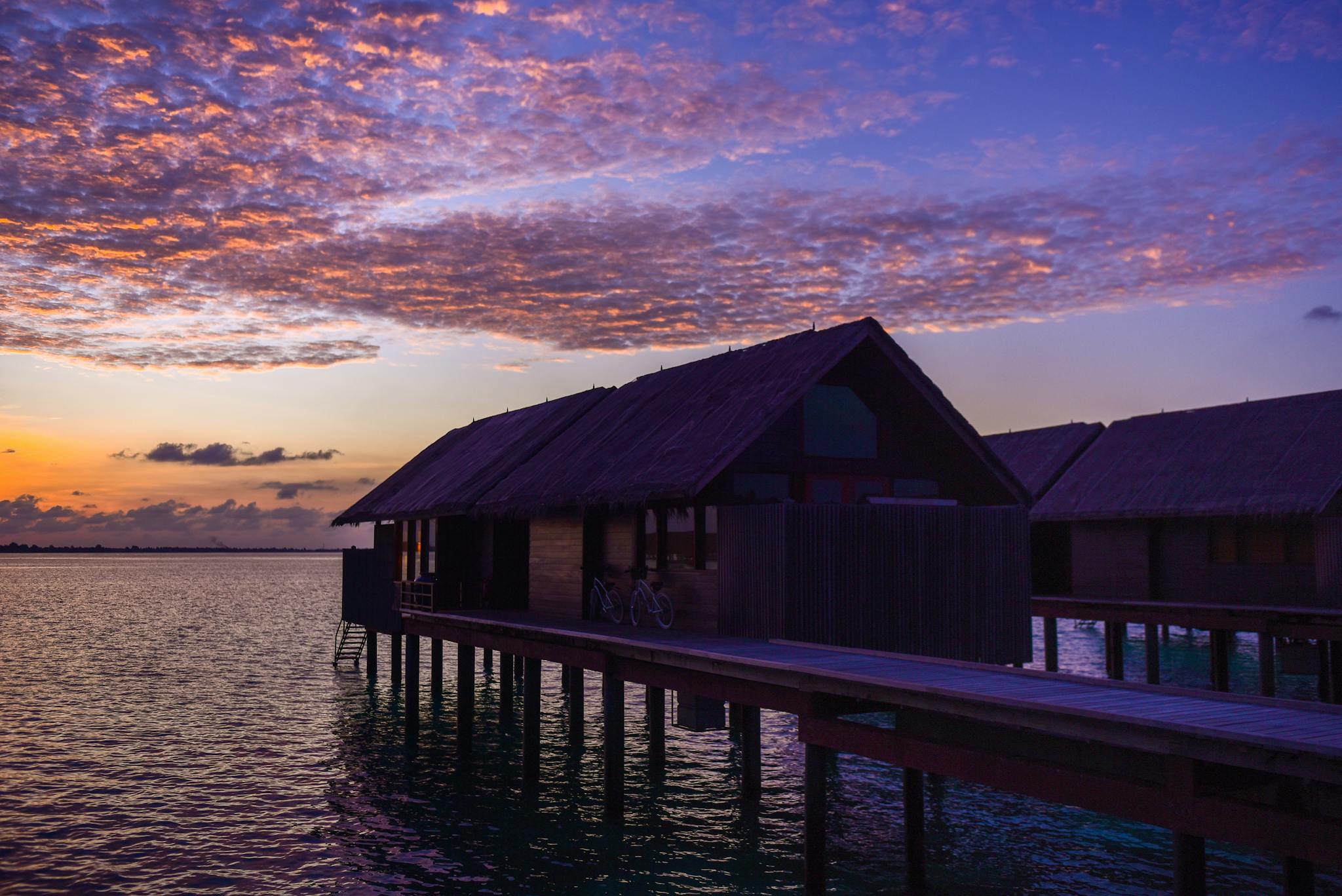 Breathtaking sunset view of overwater bungalows in a tropical paradise with vibrant skies.